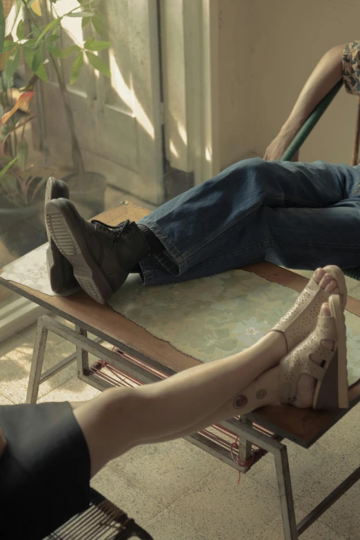 two people in denim jeans are resting on a bench