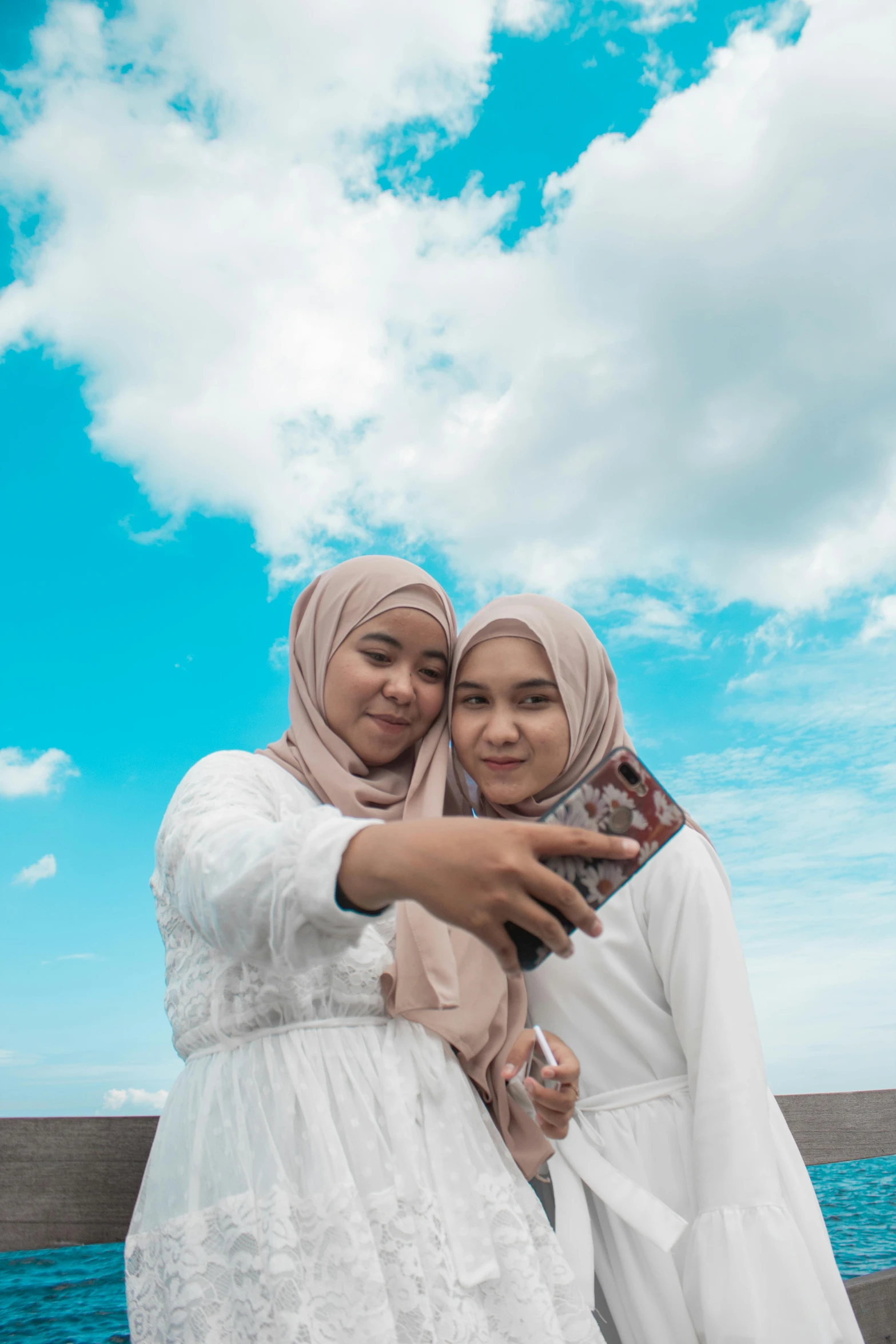 a couple of women hugging each other with a sky background