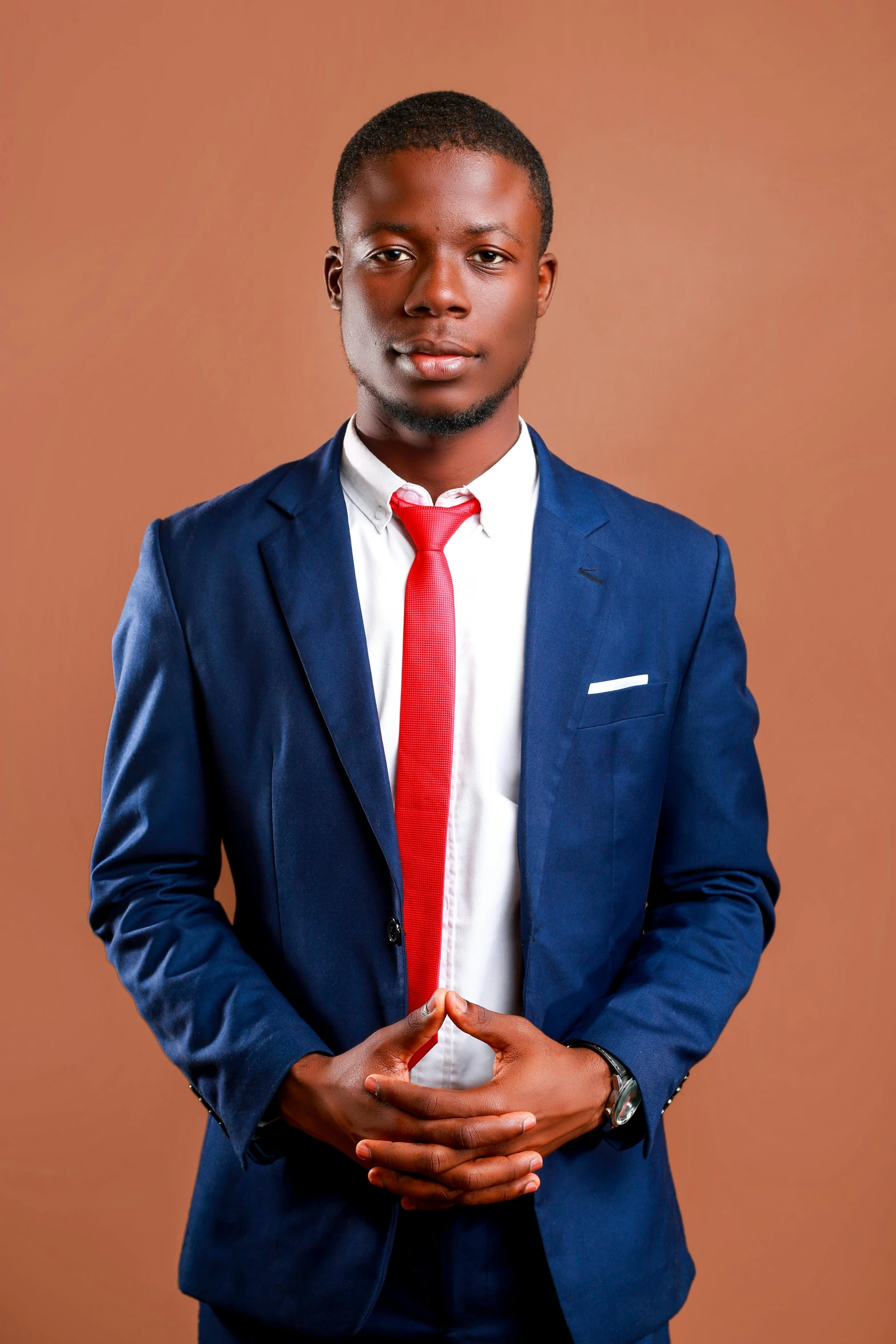 a man in a blue suit standing with his hands folded on his chest