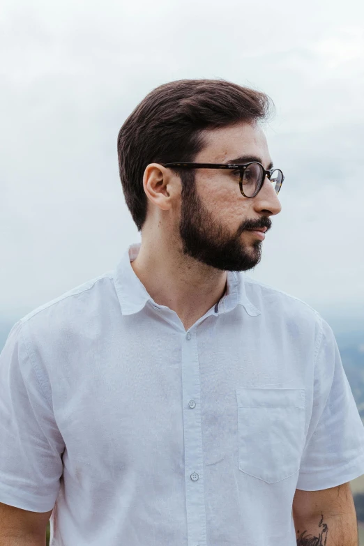 a man with glasses is standing on top of a mountain