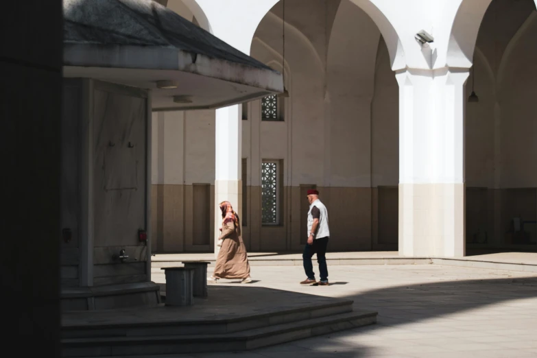 a couple walking away down a walkway in front of a building