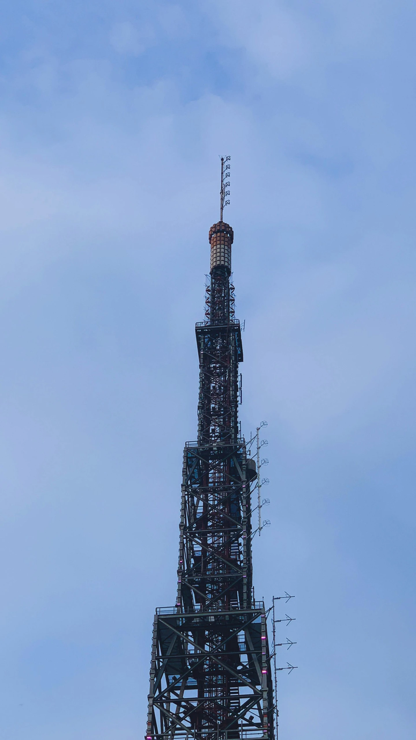 a tall tower with an orange clock and the top part covered in scaffolding