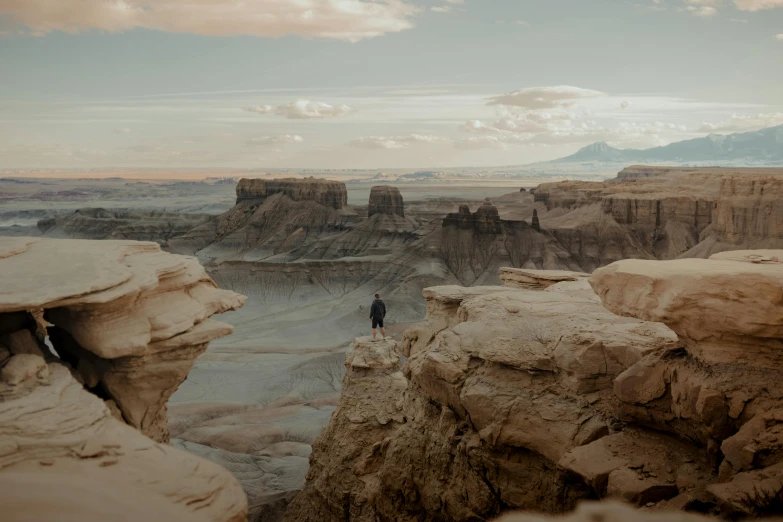 a lone person standing on top of a cliff