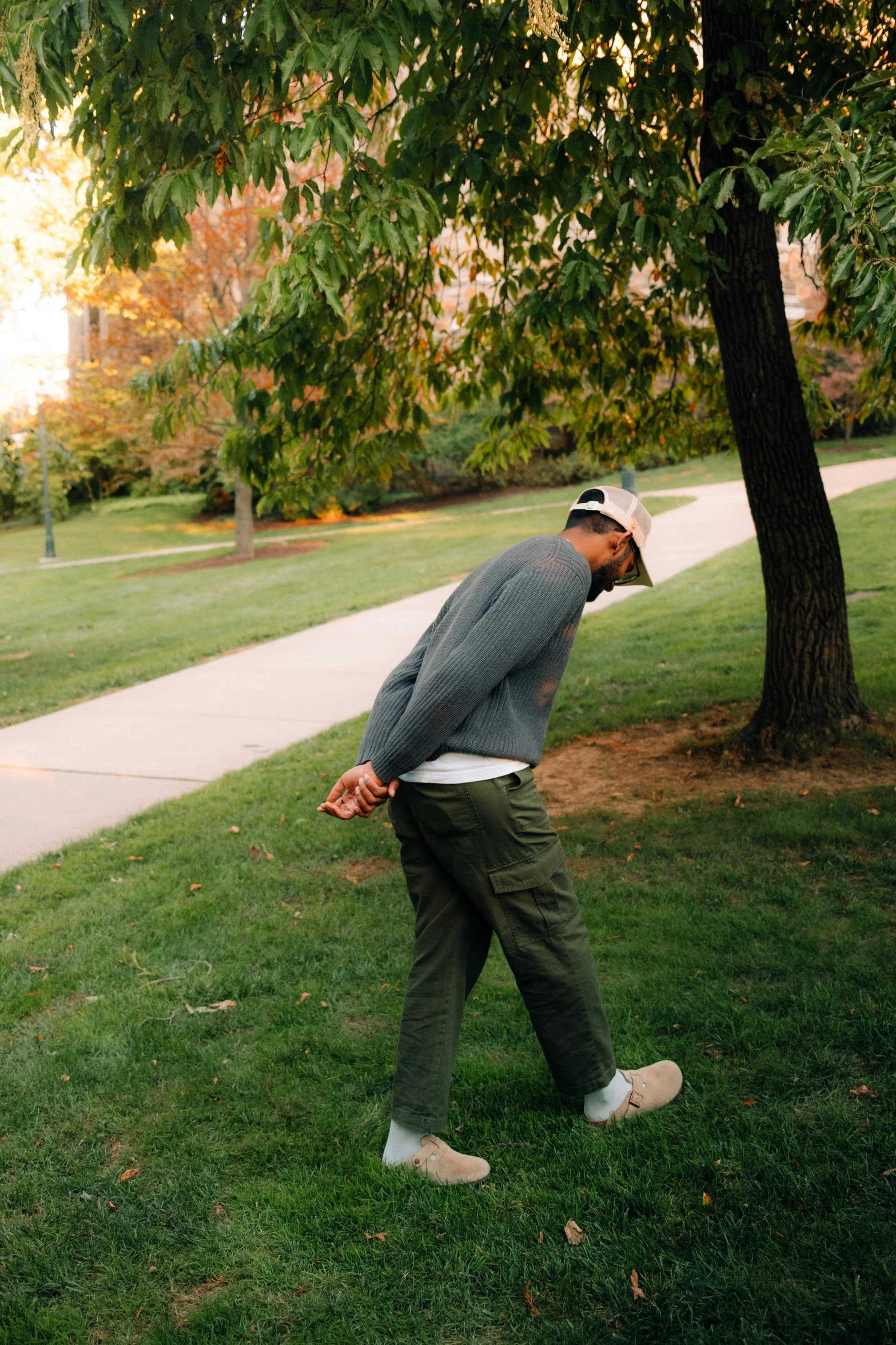 a man leaning up against a tree on a green grass covered field