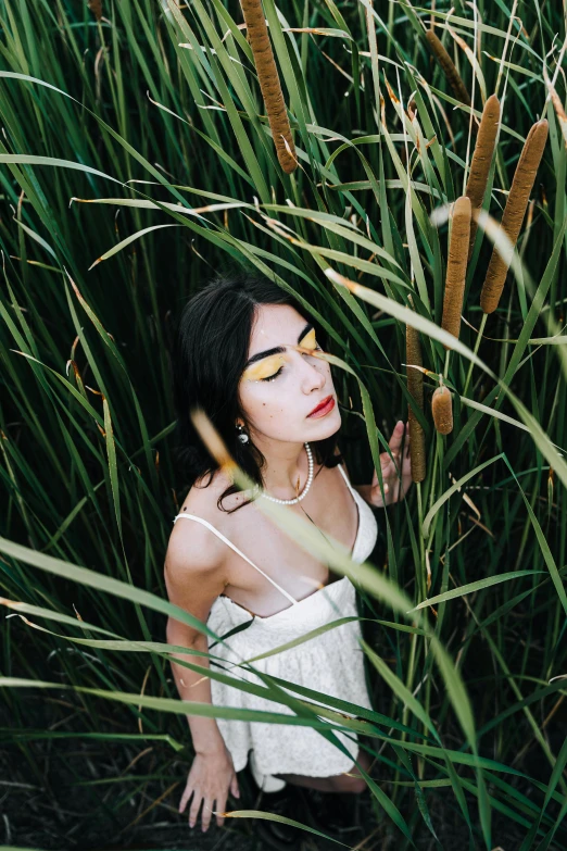 an asian woman sitting in the middle of a field of tall grass