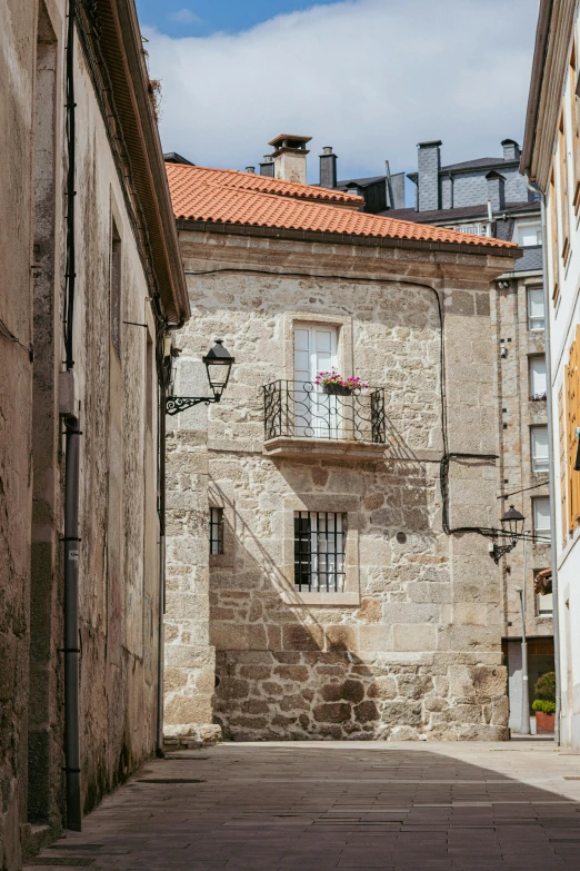 an alley in the old part of a town, with a few buildings and a blue sky