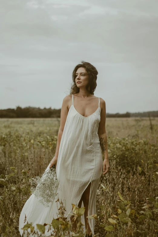 a woman in white dress standing in grass