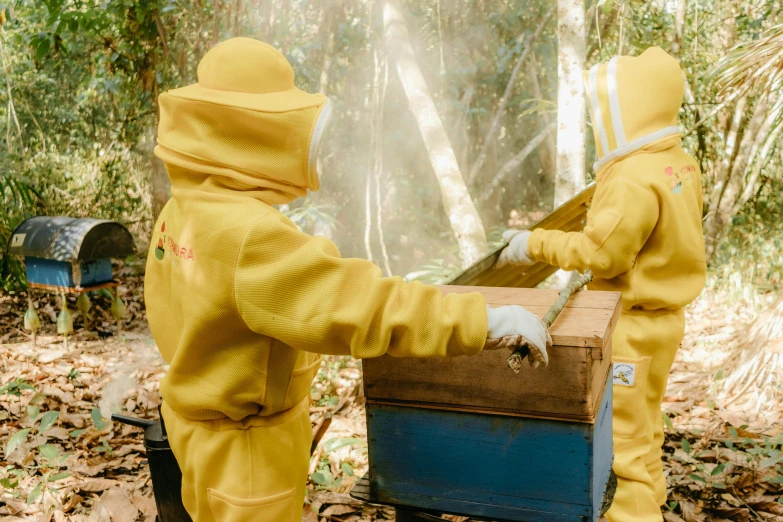 two people in bee suits are checking out a box