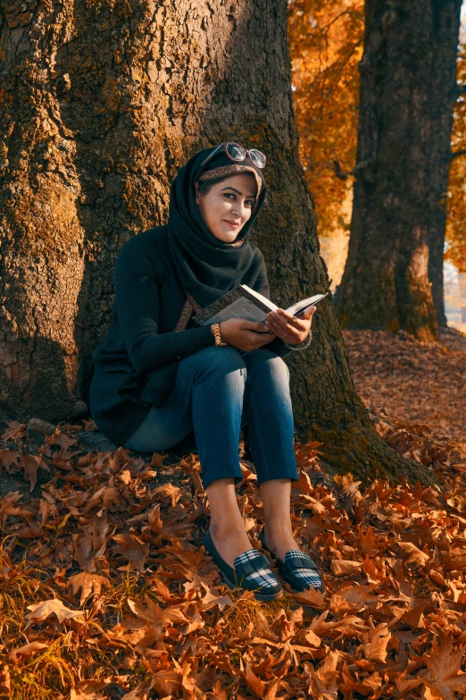 a young woman sitting on the ground while reading a book