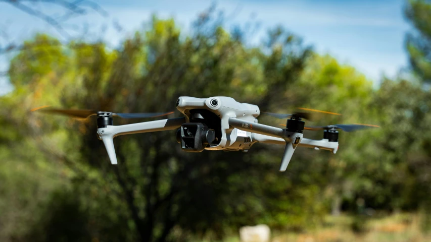 a black and white propeller flying over a forest