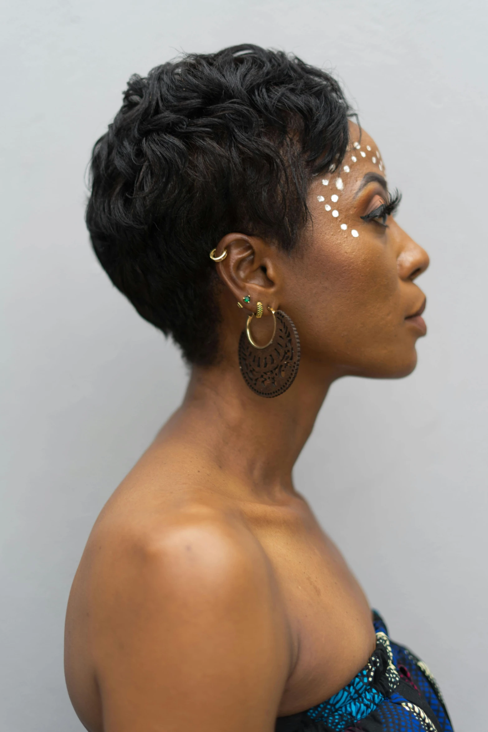 an african american woman with silver make - up and gold studs