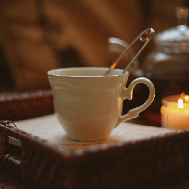 the tea cup and spoon is in front of candles