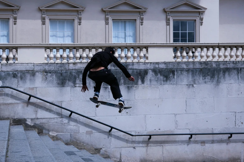 a skate boarder in a black outfit riding up some steps