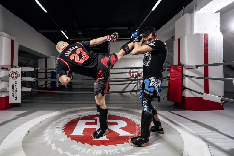 two men kick sparring in a boxing ring