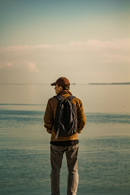 a man standing on the beach with a backpack and shoes