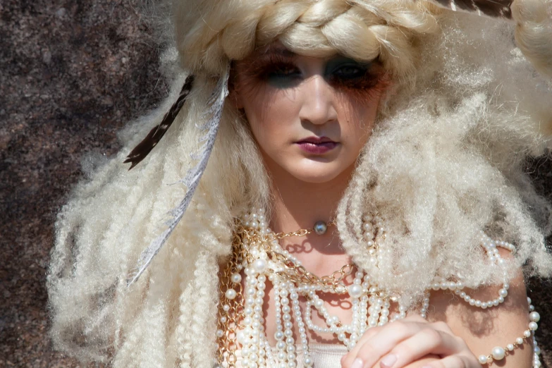 a woman with blonde hair wearing feathers and pearls