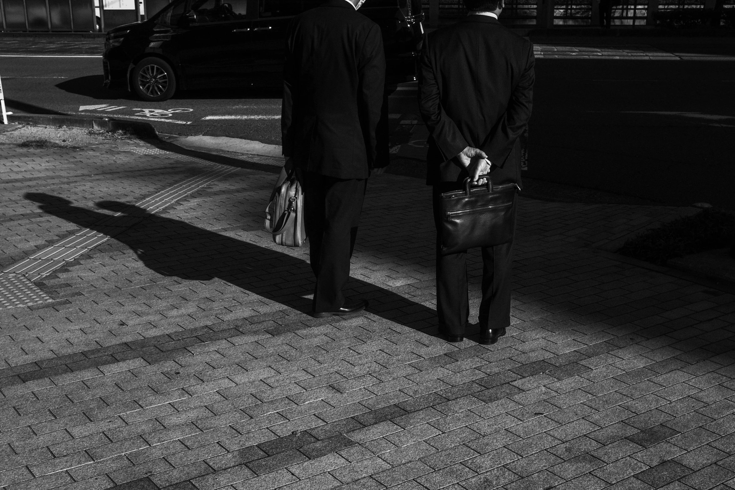 a couple of men in suits standing on a sidewalk