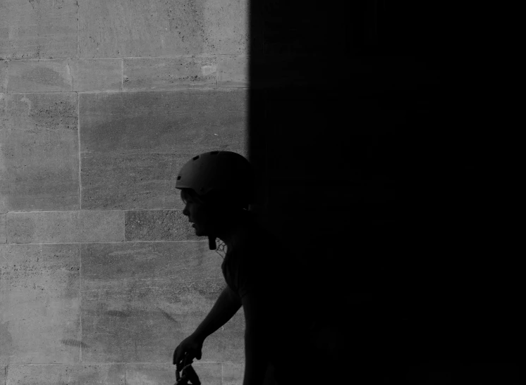 a man is holding onto a bicycle while leaning against a stone wall