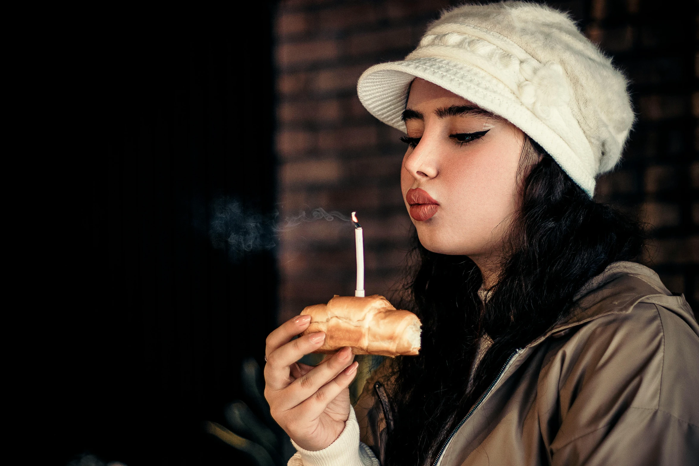 a person with a donut and a lit candle in their hand