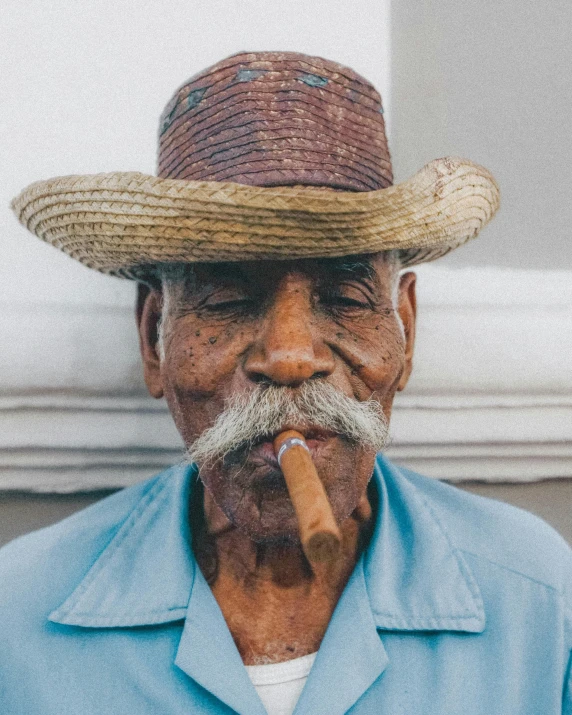 an old man with a straw hat, smoking a cigarette