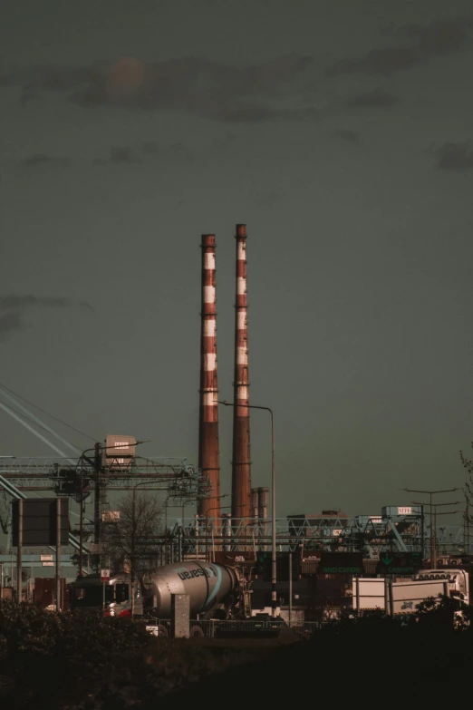 smoke stacks tower into the night sky above power lines