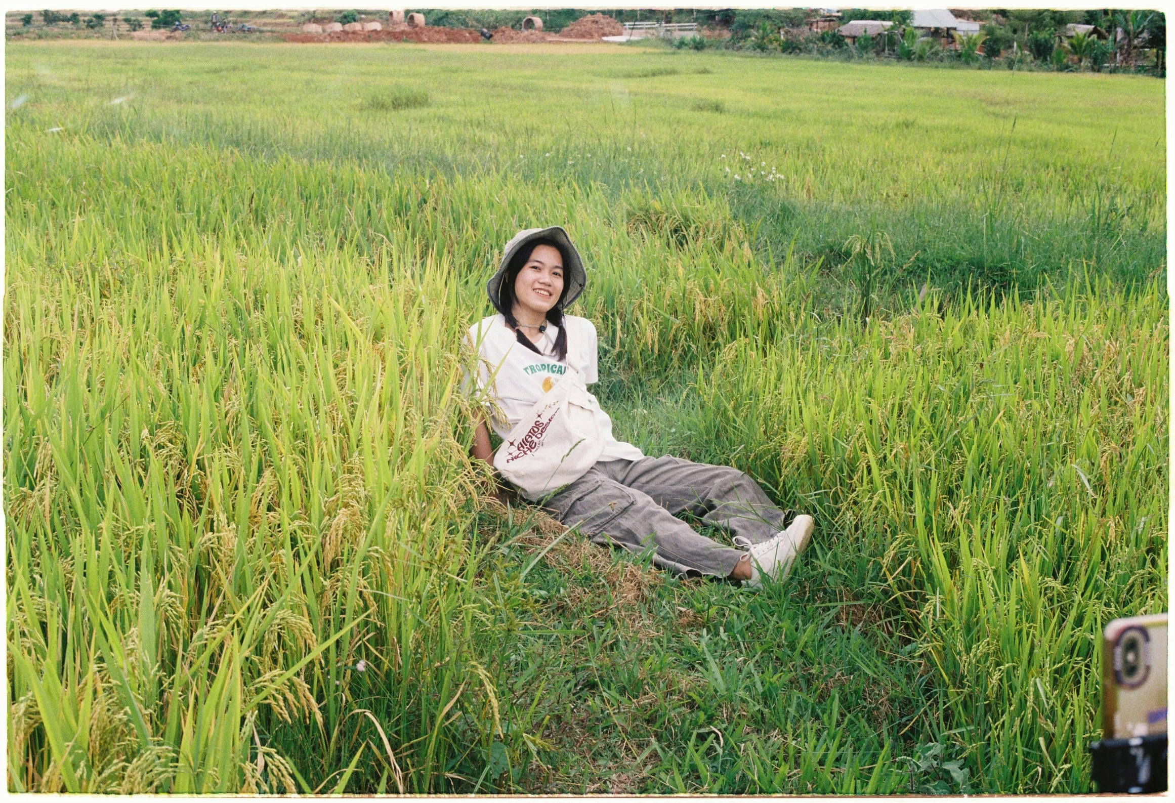 an asian woman is sitting in the middle of some tall grass