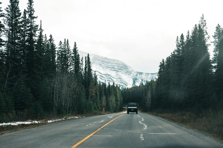 the truck travels down the road by the mountain