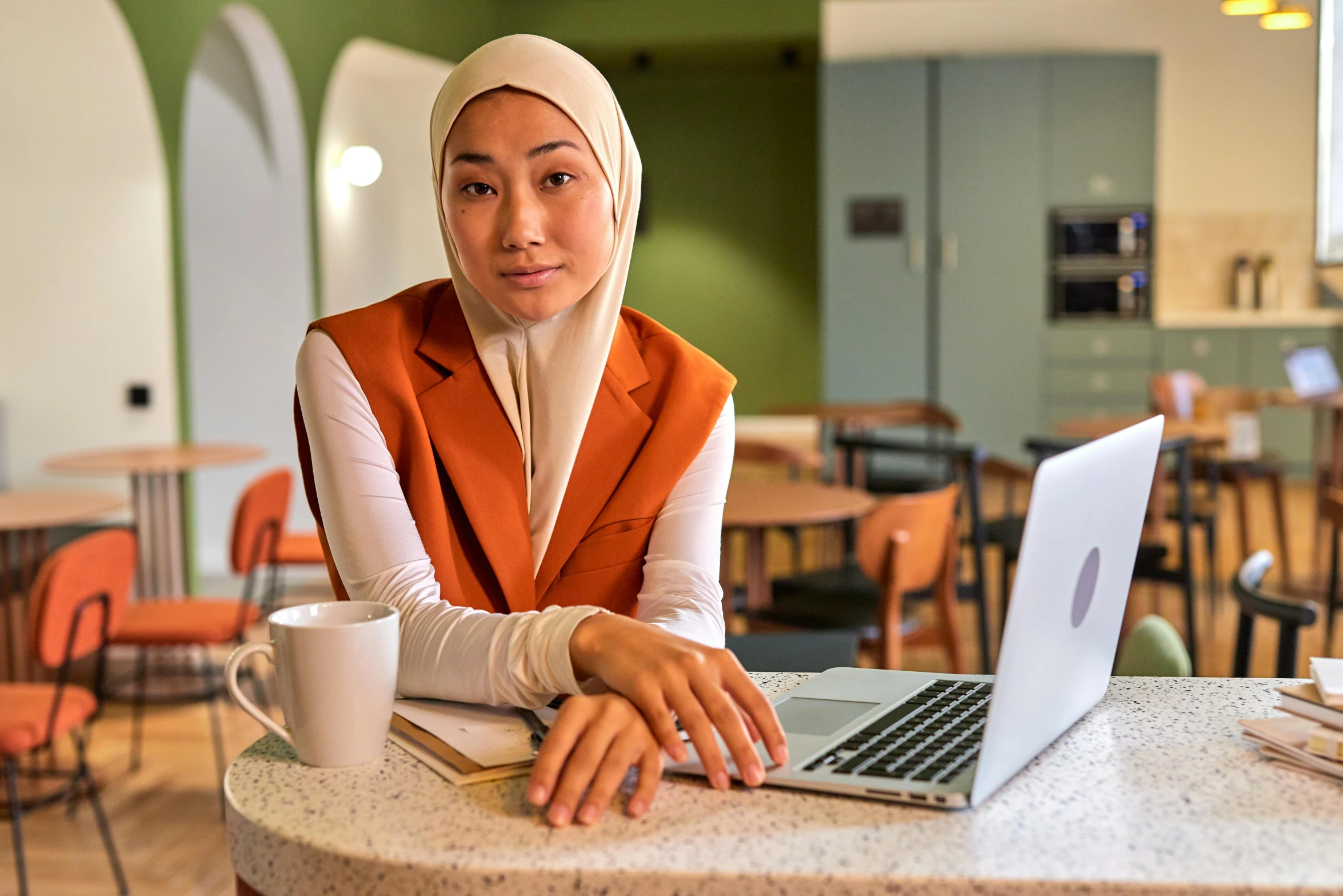 a young woman sitting at a table using her laptop