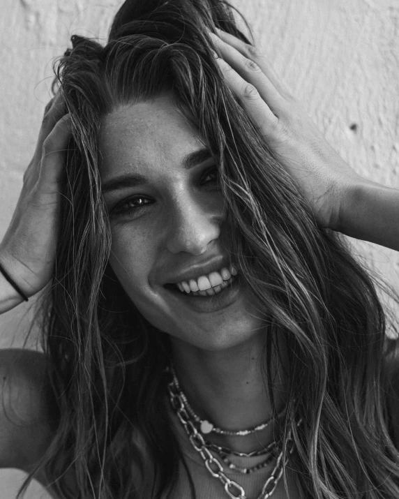 a smiling young woman with a chain necklace and rings