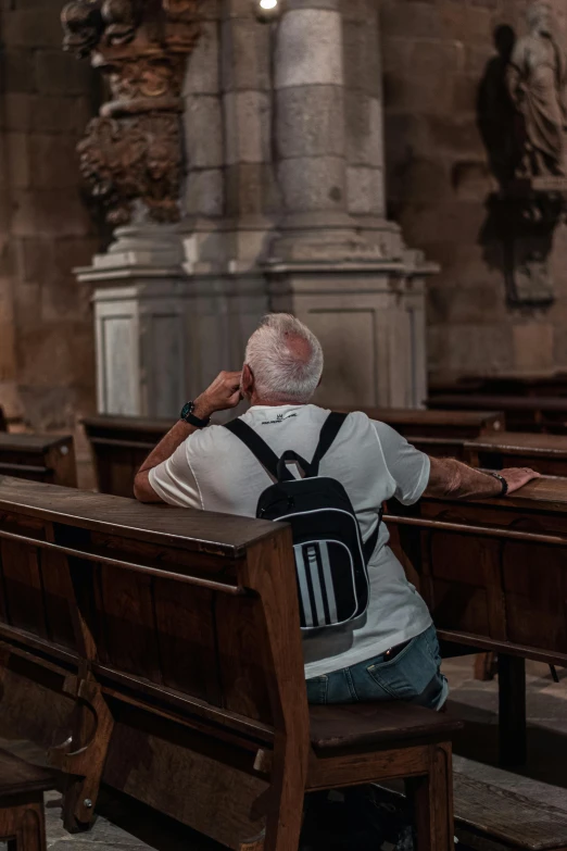 an older man sits in the pews of a catholic church