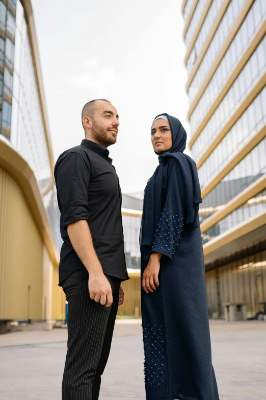 a couple is posing for a picture in front of some buildings