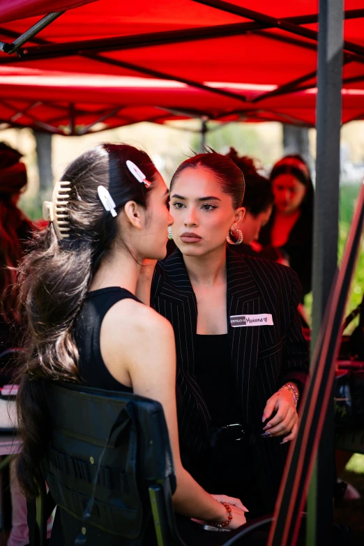 two young women having fun kissing in front of a large red umbrella