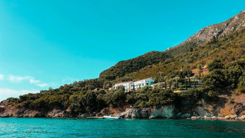 a house with blue windows and some mountains near a beach