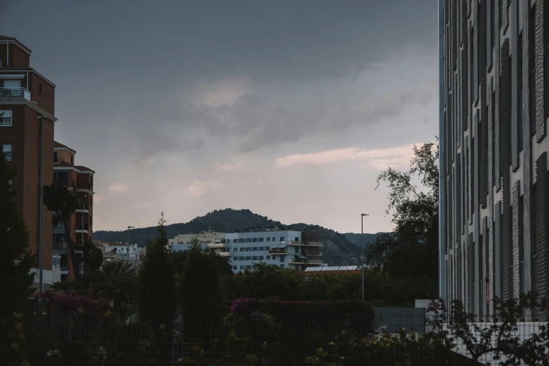 some tall buildings are against a dark cloudy sky