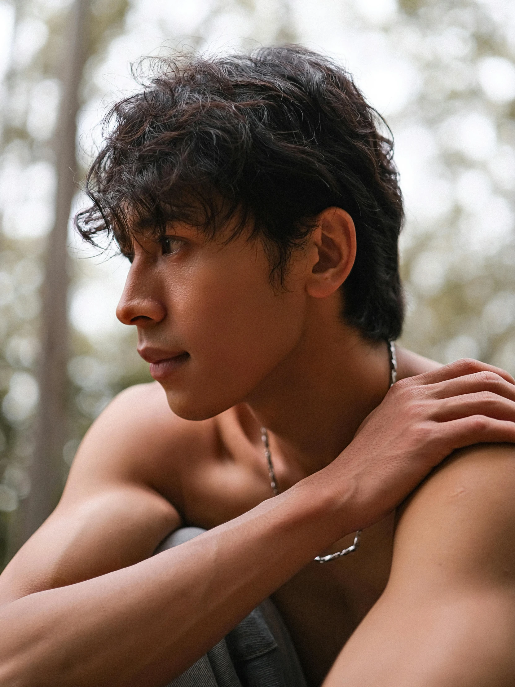 a young man wearing a white necklace