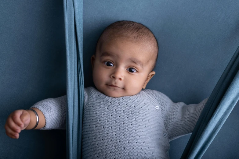 a baby looks down from behind the curtain