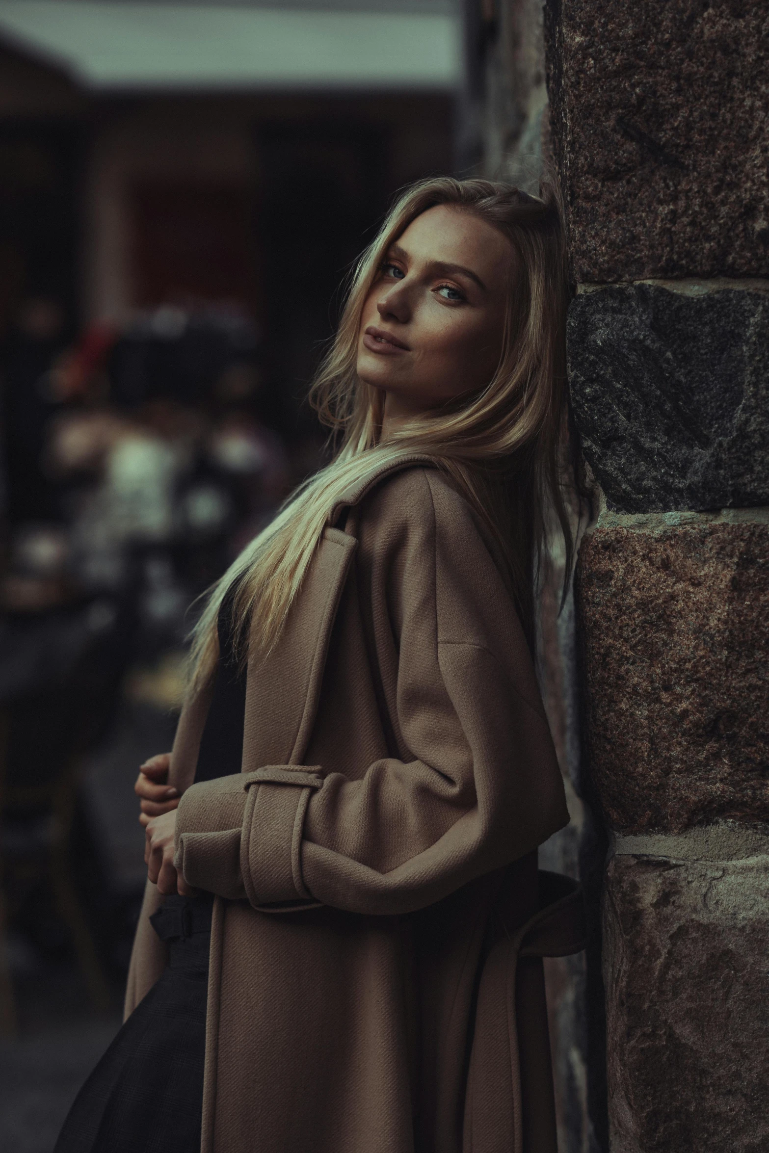 a woman leaning on a stone wall next to a tall brick building