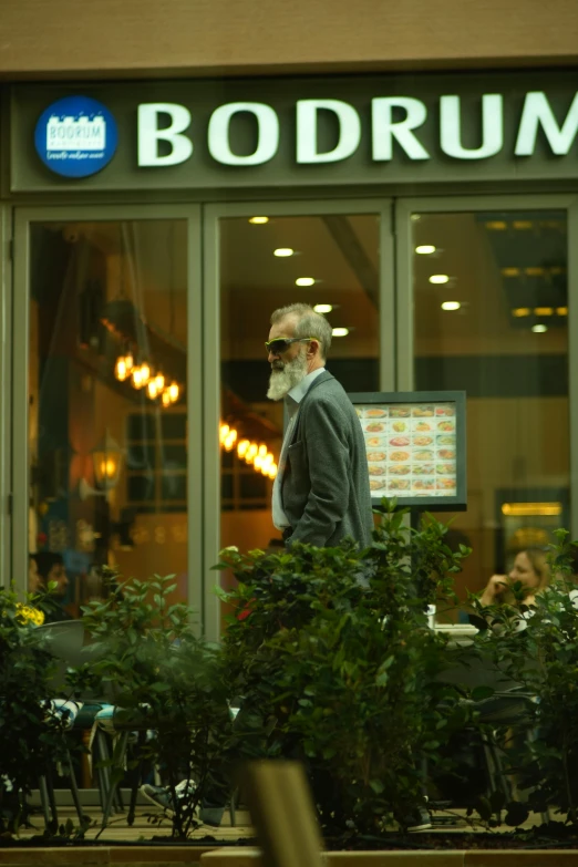 a man walking outside of a restaurant by a large sign