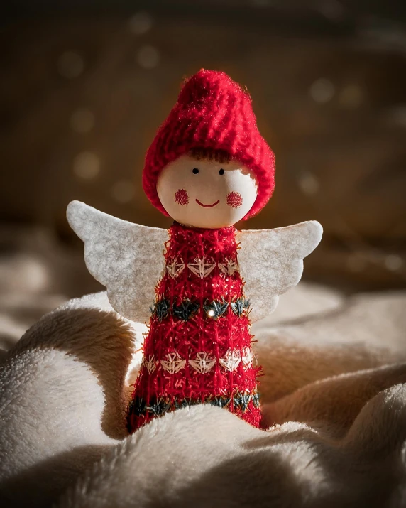 a red knitted fairy doll sits on the blankets