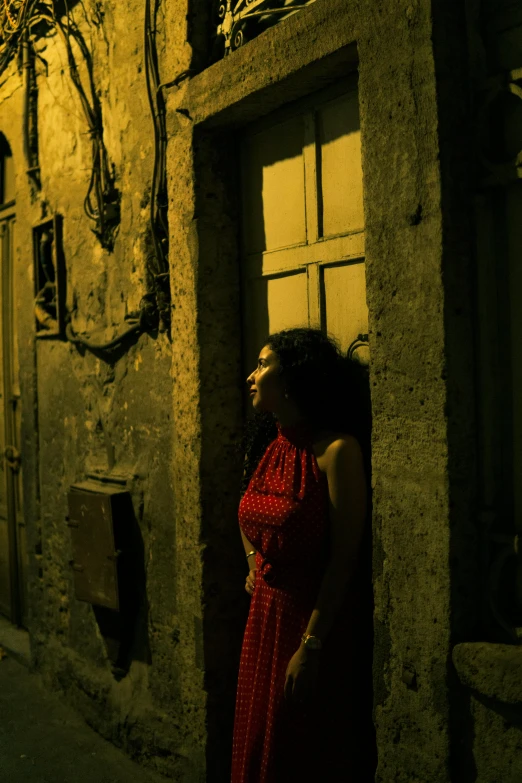 a woman wearing a red dress walking towards a building