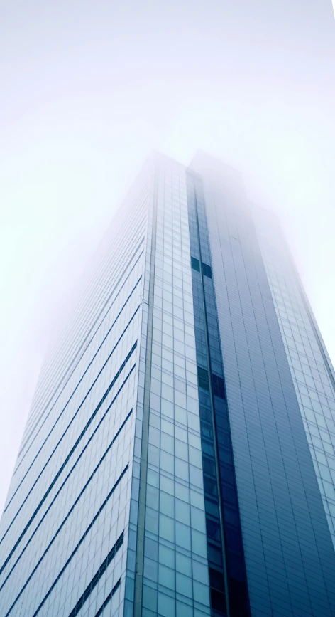 an upward view of the side of a tall skyscr with some clouds