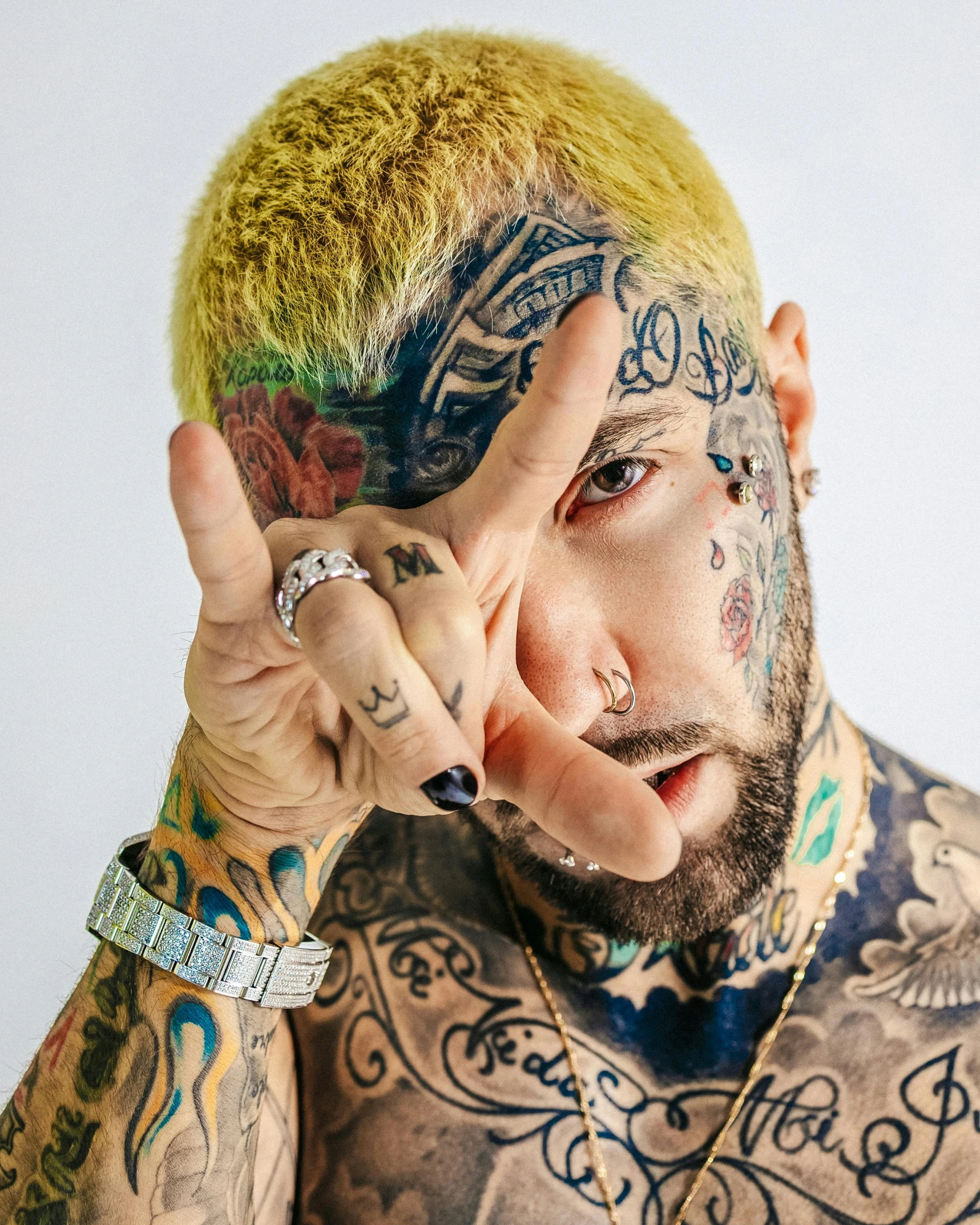 tattooed man posing for the camera while holding up his peace sign