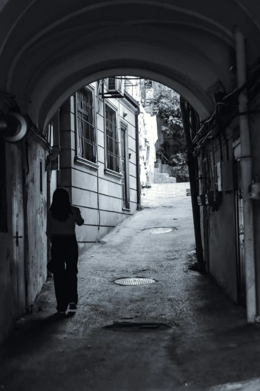 a woman carrying an umbrella is going down an alley way