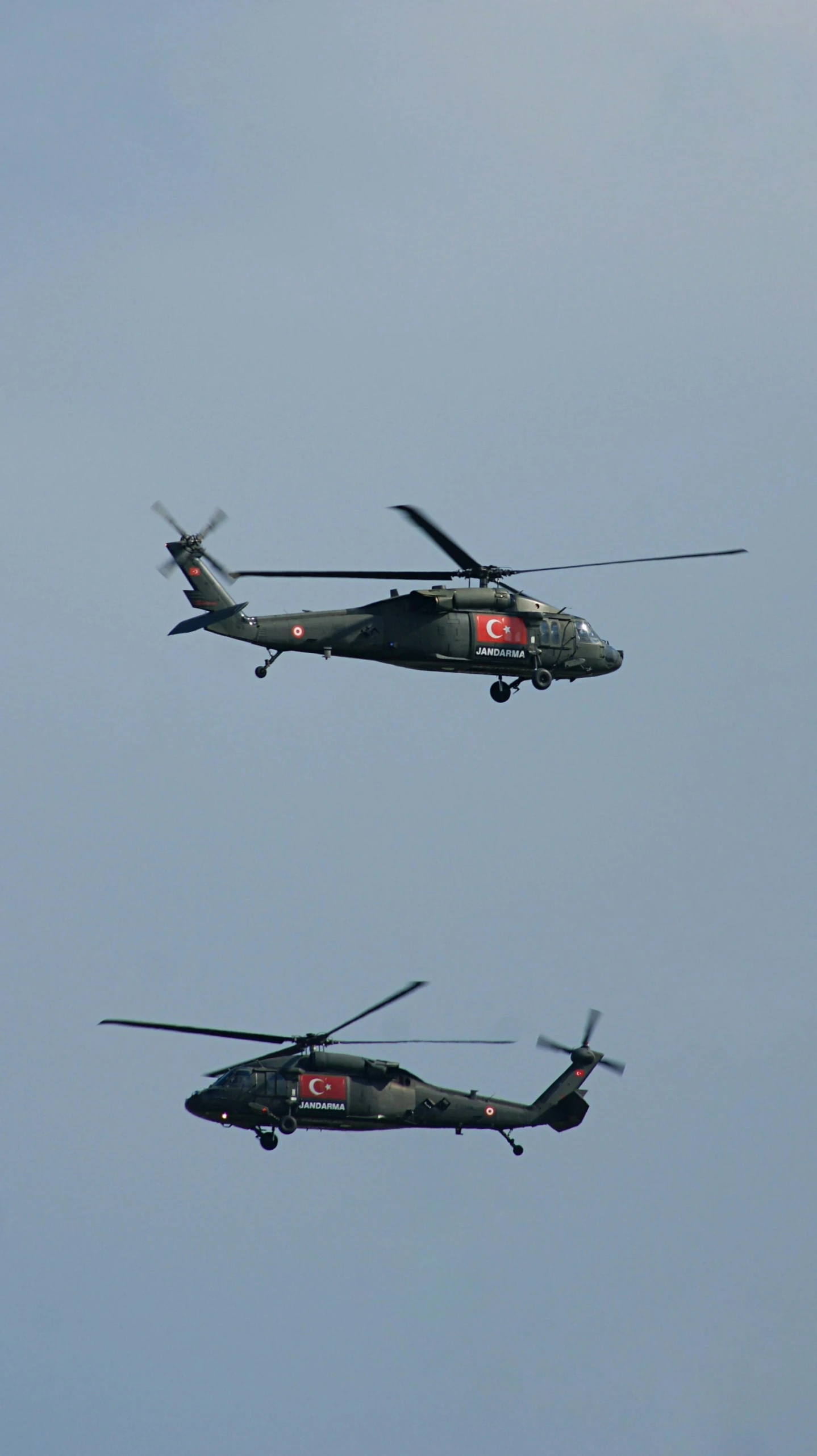 two military helicopter flying side by side through the air