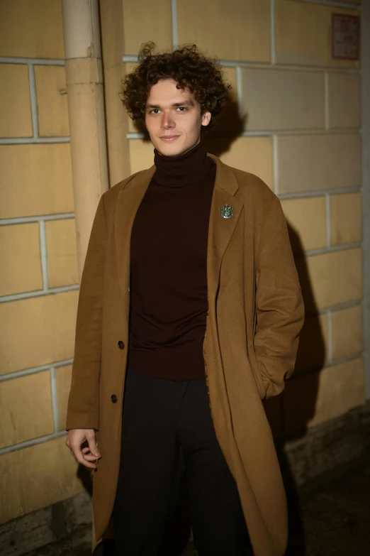 the man in a camel coat is posing