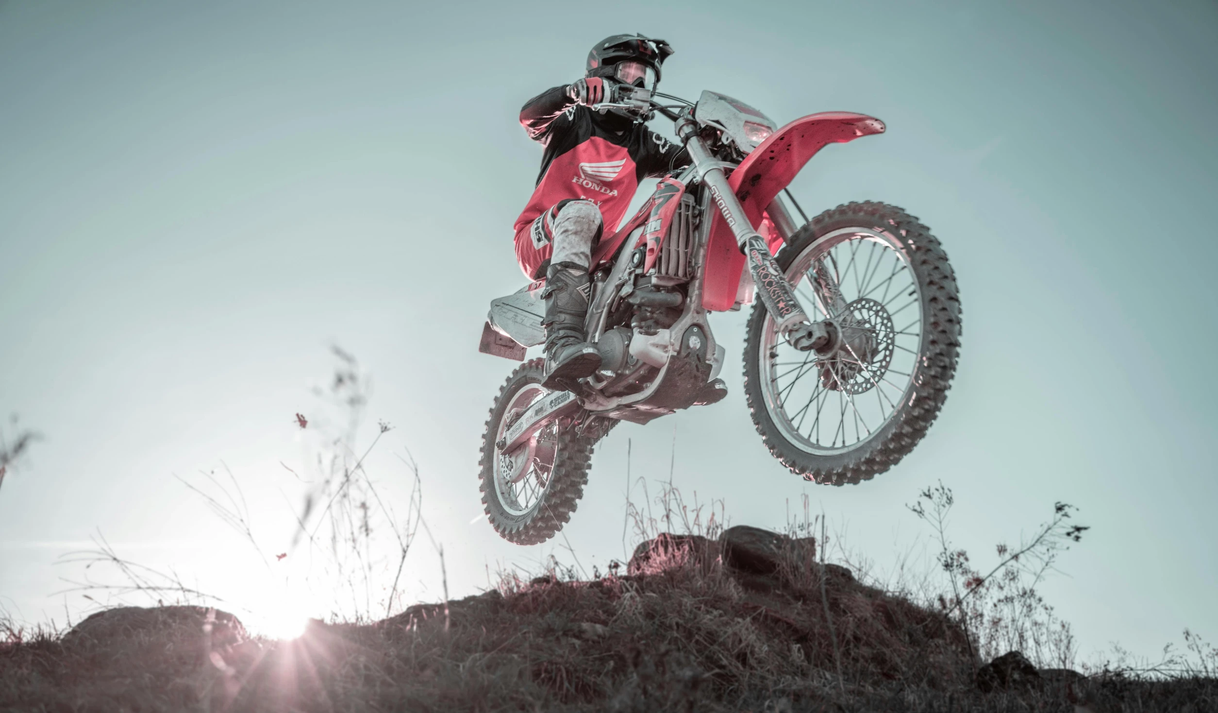 a man on a red dirt bike doing a trick