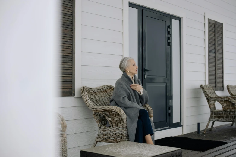 an older woman sitting in the porch of a house