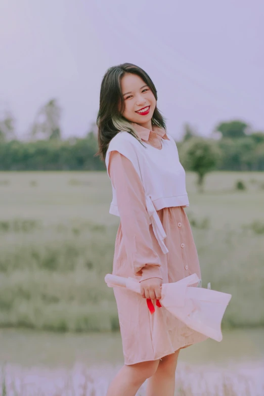 a woman standing on top of a field wearing a pink dress