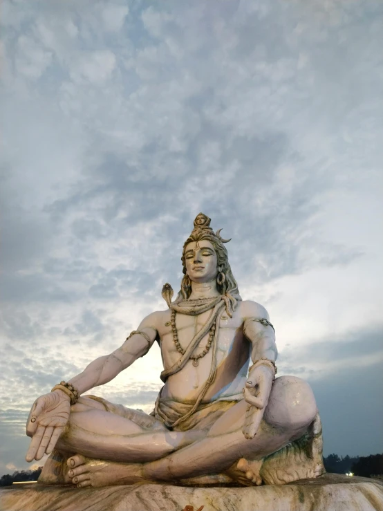 a man sitting on a statue with his hands folded in the air