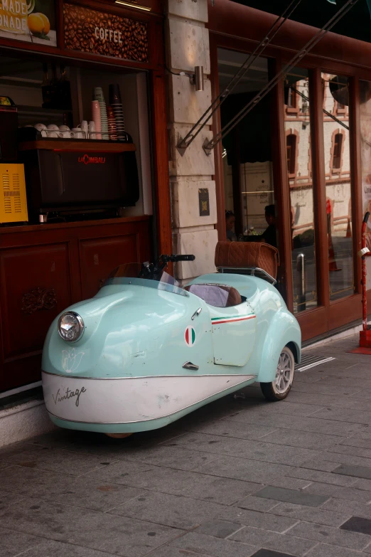 an old model of an electric car in front of a coffee shop